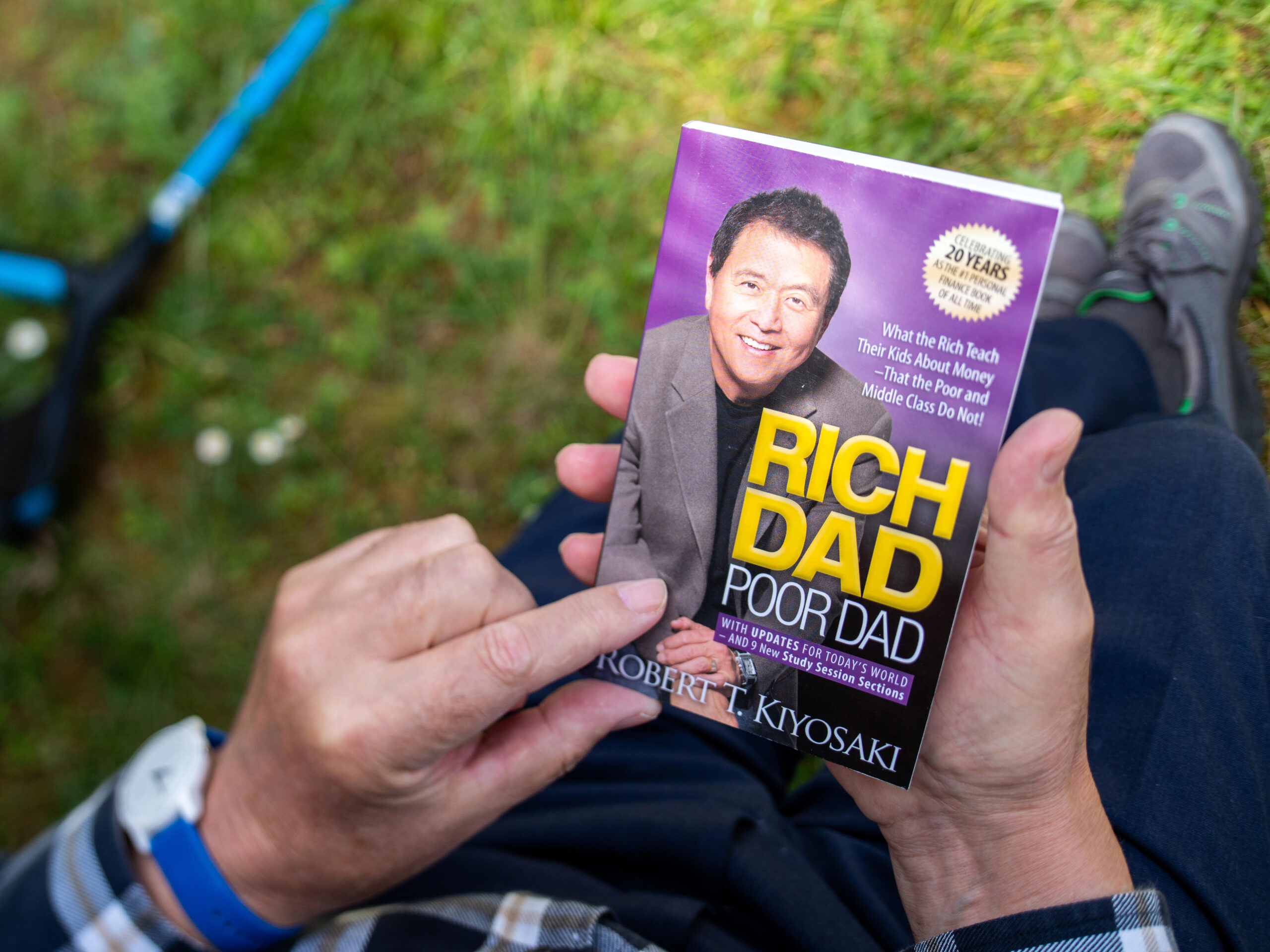 Hands holding a copy of the personal finance book Rich Dad Poor Dad